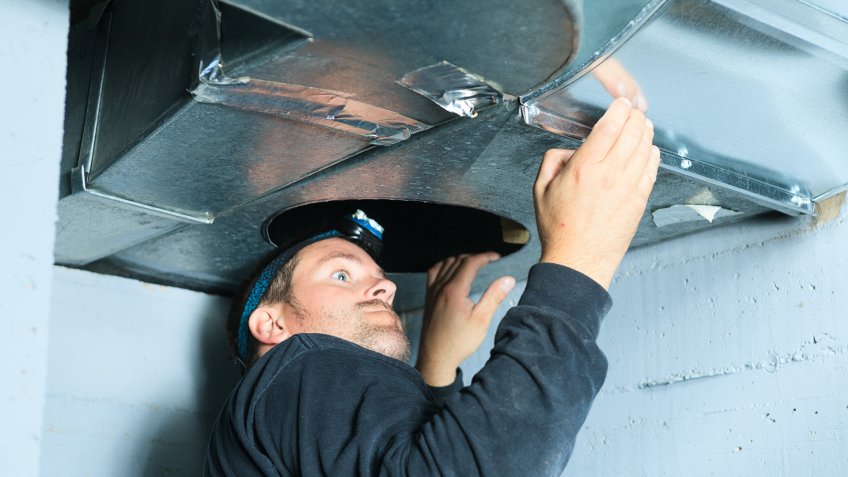 man sealing heating and cooling duct in house