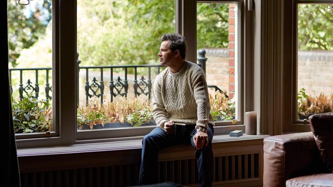 Shot of a man looking through his living room window.