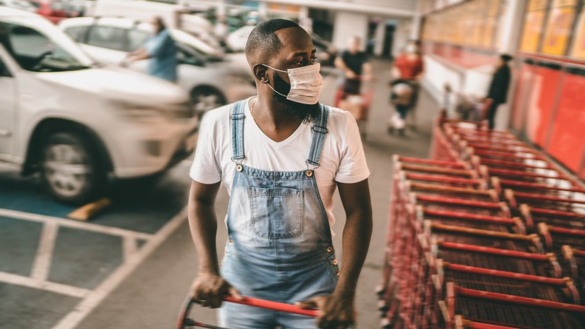 Men wearing face mask picking shopping cart in supermarket.