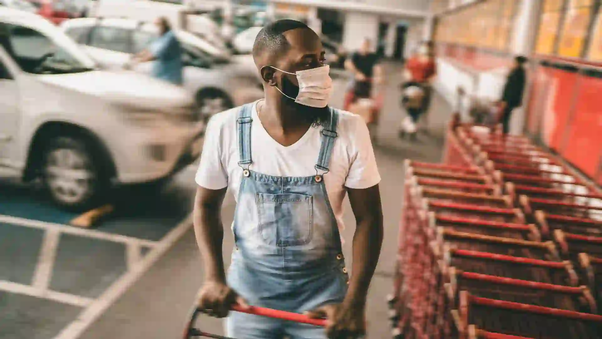 Men wearing face mask picking shopping cart in supermarket.