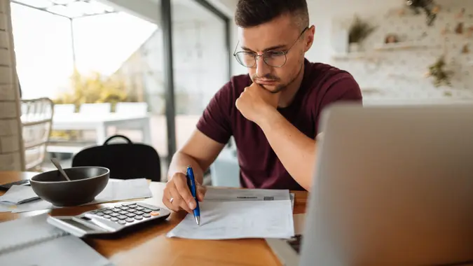 Young man at home, paying bills online.