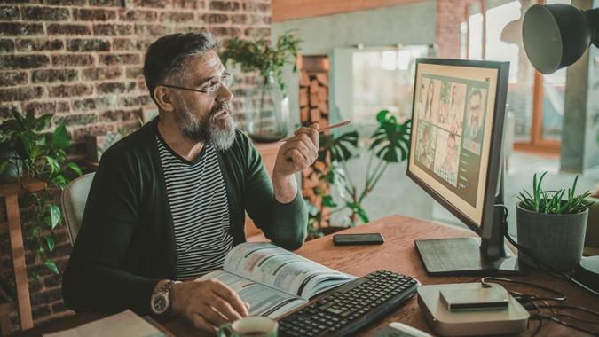 Mature teacher at home during pandemic isolation teaching students online.