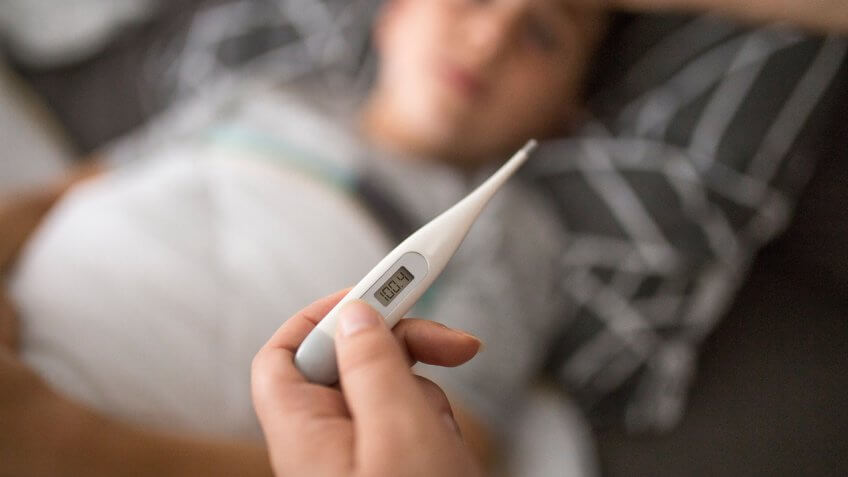 Mother checking her sick sons temperature.