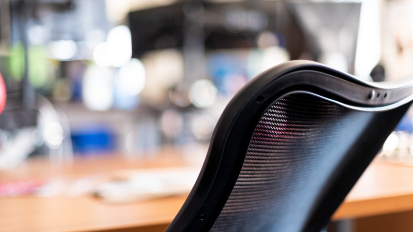 Wooden home or office room in closeup of black chair and bokeh background of computer electronics and empty space in workplace or house.