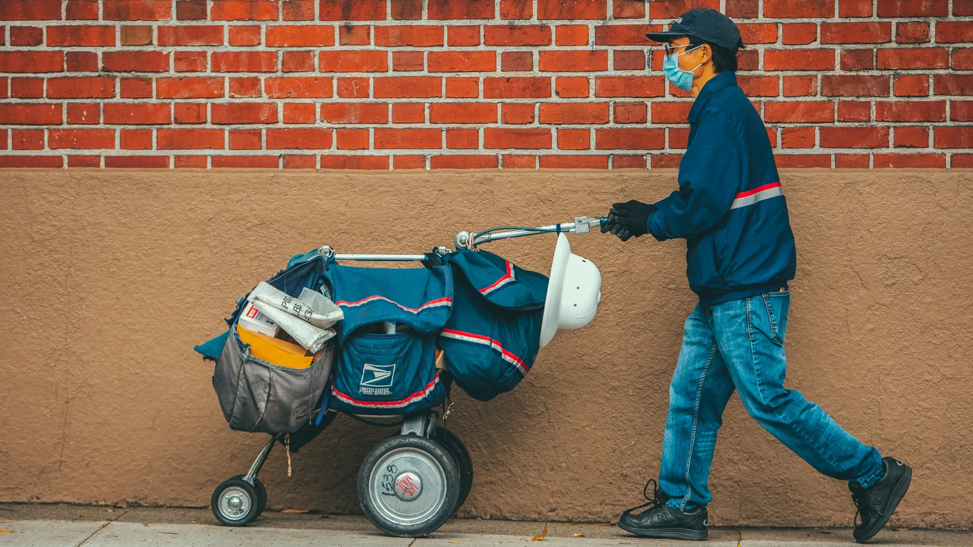 San Francisco, USA - April 4, 2020: San Francisco postal worker in mask delivering mail during stay-at-home order.