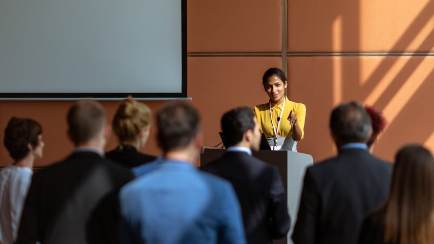 An Indian female presenter interacting with the audience at a business presentation in the board room.
