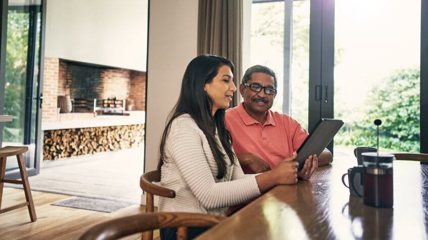 Shot of a young woman using a laptop with her father at home.
