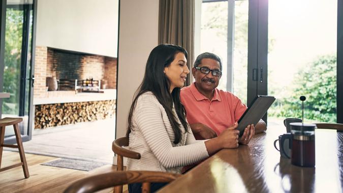 Shot of a young woman using a laptop with her father at home.