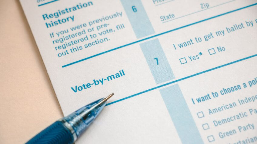 Closeup of voter registration form, focused on the Vote-by-Mail section with pencil on top.