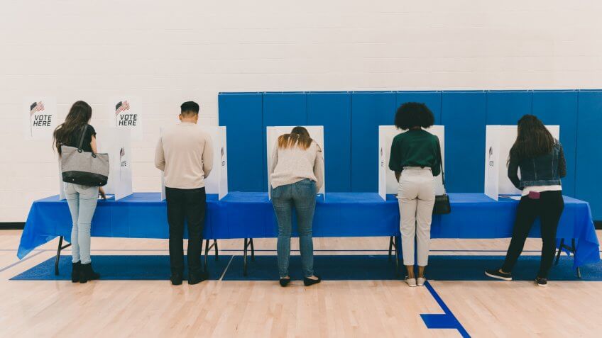 A rear view of a multi-ethnic group of people casting their ballots in the election.