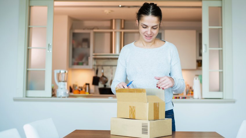 A woman opening boxes containing products she purchased online.