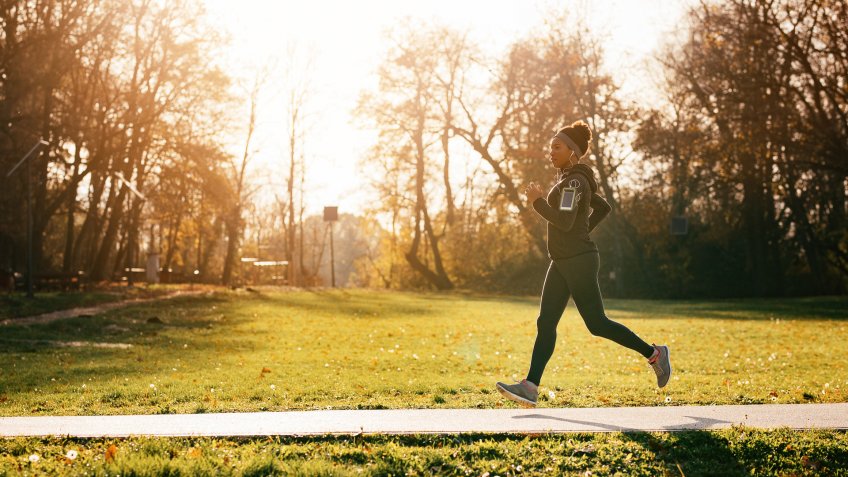 Full length of black sportswoman jogging in nature.