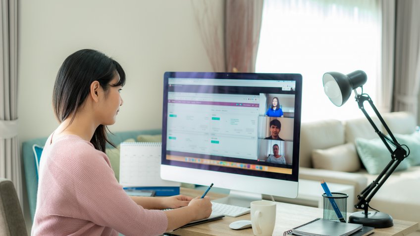 Back view of Asian business woman talking to her colleagues about plan in video conference.