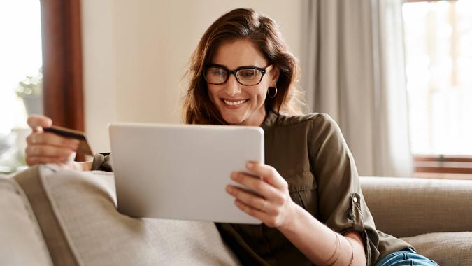 Cropped shot of an attractive young woman using a digital tablet and a credit card to shop online while sitting in her living room at home.