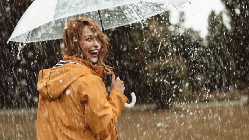Cheerful pretty girl holding umbrella while strolling outside.