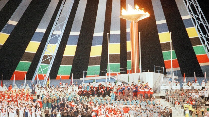 Athletes gather under the Olympic torch during the closing ceremony at the McMahon Stadium in Calgary at night on .