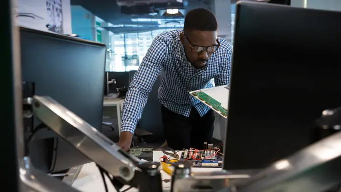 Computer engineer repairing motherboard at desk in office.