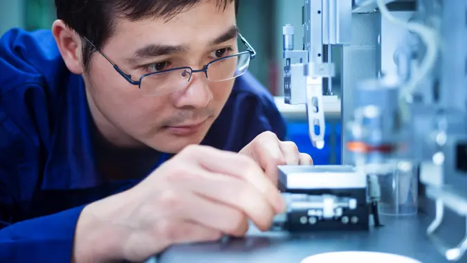 Image shows a man inserting something into a scientific device. Depicts QC inspector engineer STEM worker researcher in concept.