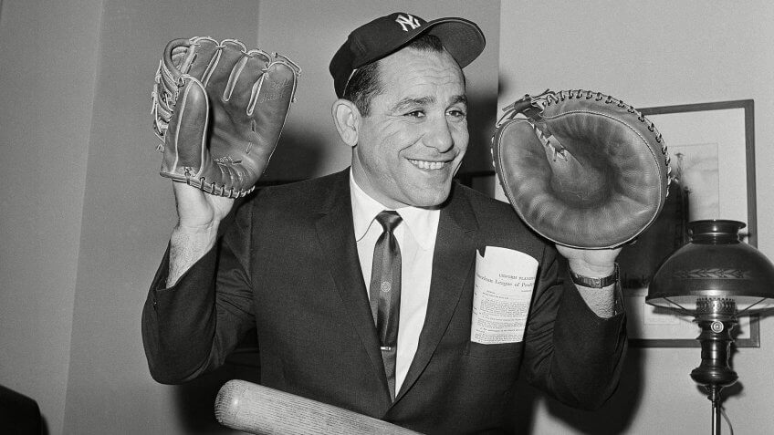 Yankee veteran Yogi Berra wears catcher's mitt and fielder's glove, as he sits in the downtown office of the New York Yankees in New York, after signing his contract for 1961.