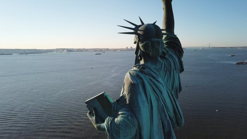 NEW YORK - MARCH 11, 2018: aerial view of Statue of Liberty from the rear overlooking blue water in NYC. The statue stands 305 feet and 1 inch from the ground.