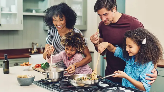 A shot of a family of four cooking together in their home kitchen.
