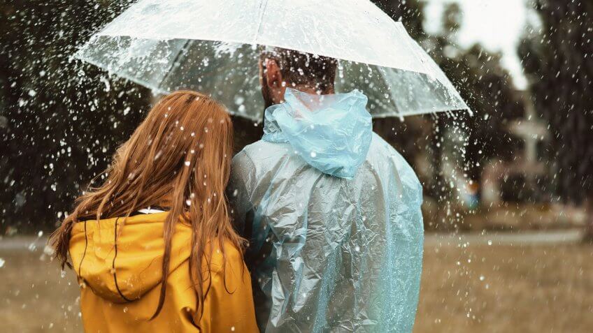 Male and female strolling under one umbrella together.