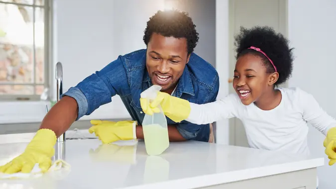 Shot of a little girl and her father enjoying their chores at home.