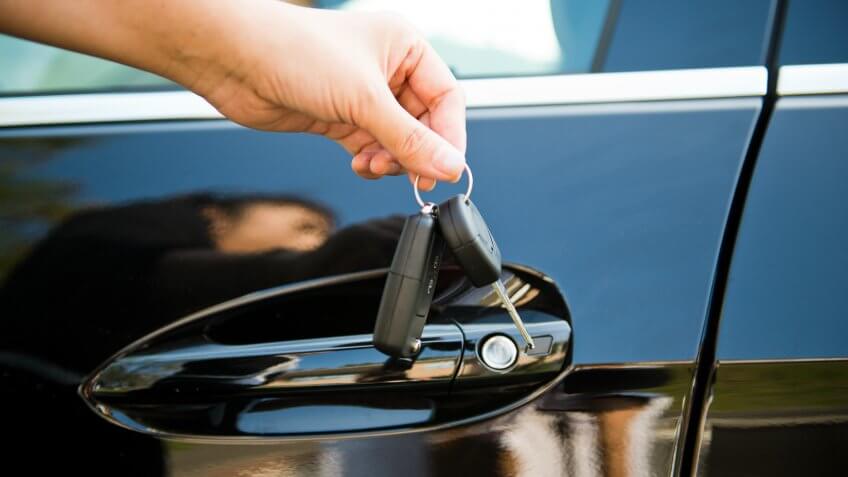 Image of human hand holding a car key a remote control.