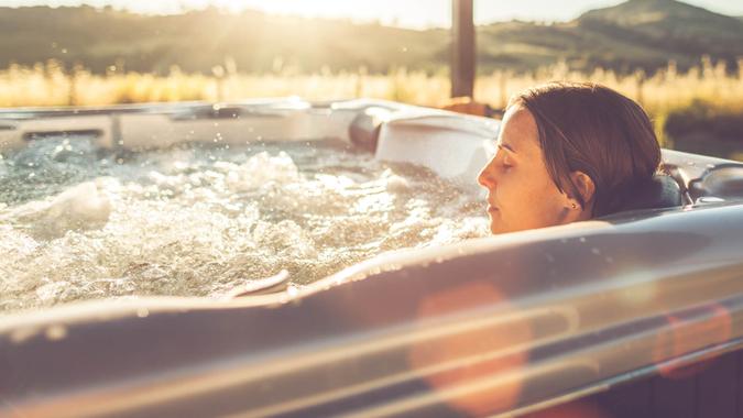 Woman in whirlpool hot tub at sunset.