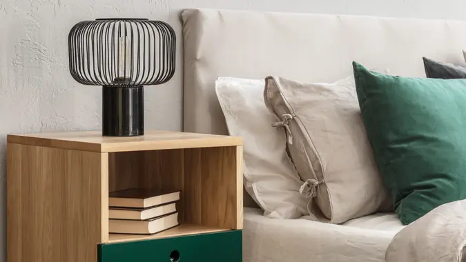 Beige and emerald bedroom design with modern lamp on wooden nightstand table.