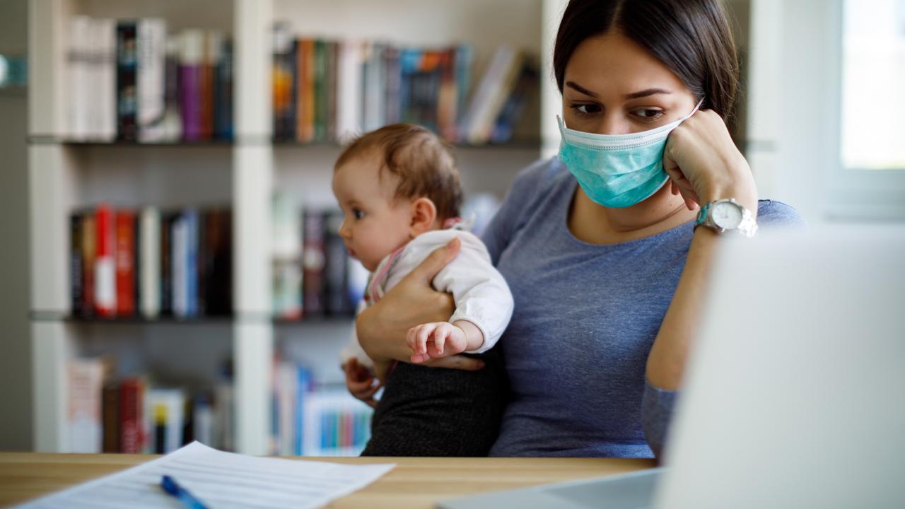 Worried mother with face protective mask working from home.