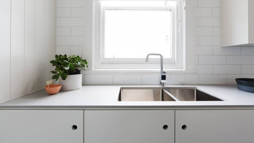 Close up details of contemporary white apartment kitchen with subway tiles.