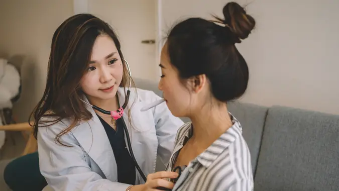 an asian chinese female doctor examing an chinese female patient during her home visit.