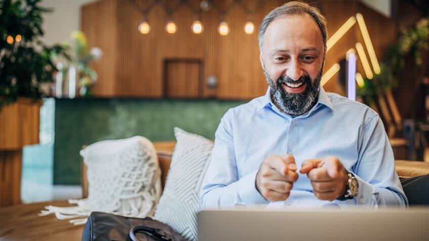 Happy men in hotel lobby talking with his family via skype while he is on his business trip.