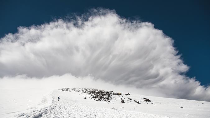 Stormy clouds surging above the snow-capped mountain Elbrus at sunset.