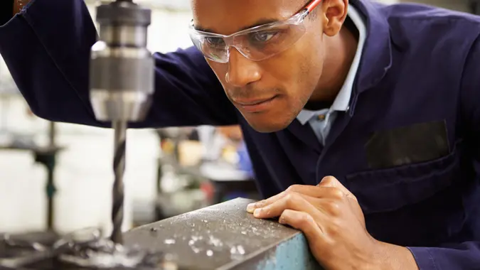 Close Up Of Apprentice Engineer Using Milling Machine.