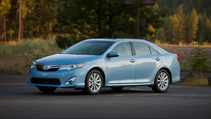 2014 Toyota Camry Hybrid parked on a road for a promotional picture.