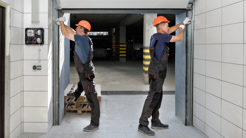 Workers are installing lifting gates of the garage.