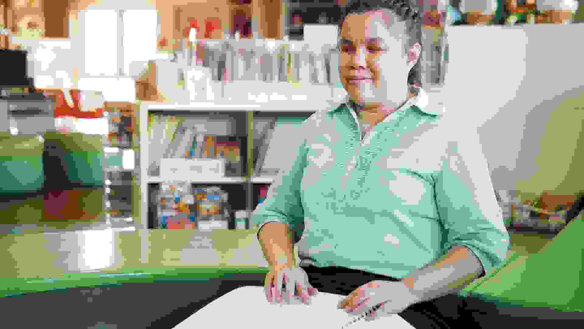 Portrait of Asian young blind woman disabled person reading Braille book in creative workplace.