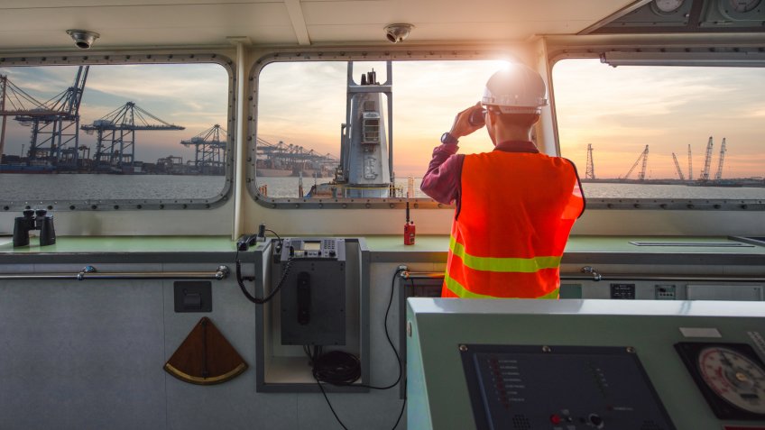 pilot, port control or duty officer in charge handle of the ship navigating to the port destination, keep watching navigation on the bridge of the ship vessel under voyage sailing to the sea.