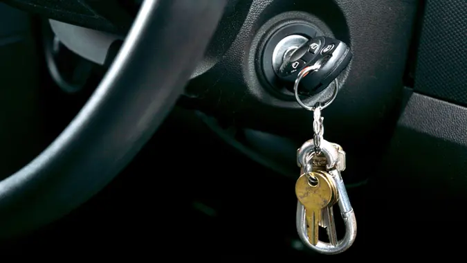 Shot of Car key and house key dangling from the ignition of car.