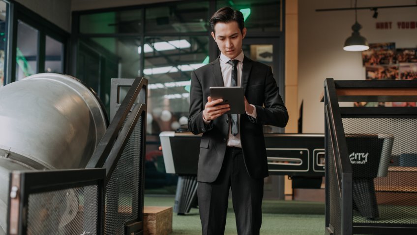 an asian chinese male young executive using digital tablet surfing the net in a cafe.