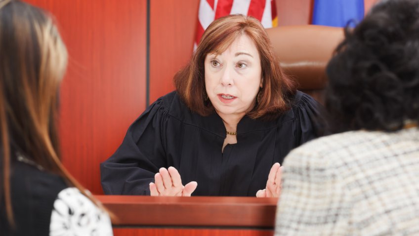 Two female lawyers speaking to a Judge in the courtroom.