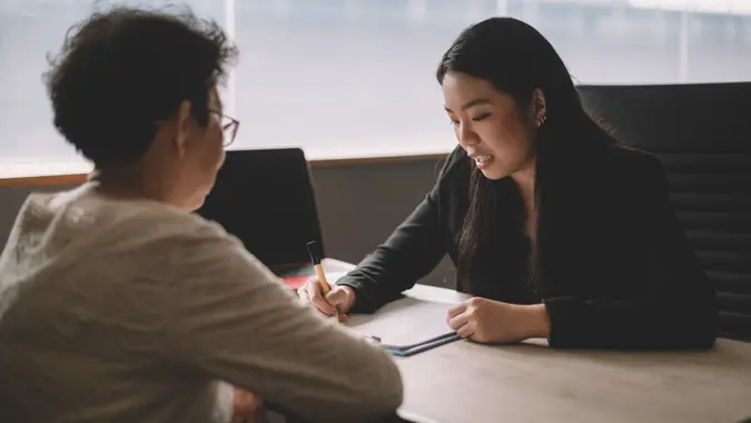 an asian chinese active senior woman having discussion with her chinese agent about her retirement investment plan.