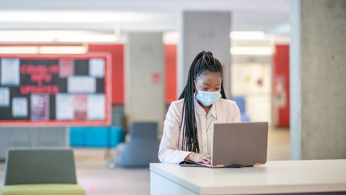 African American woman works in the new workplace with a mask on.