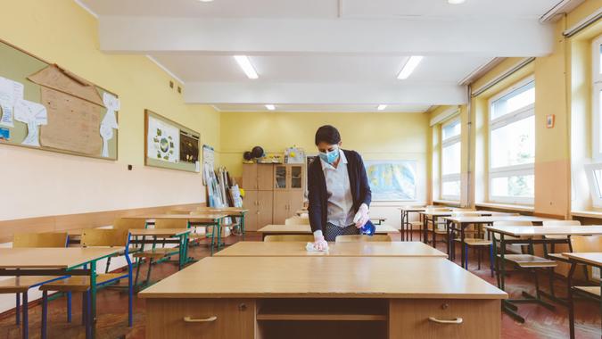 The teacher wipes down tables in the classroom before students return to school after the coronovirus pandemic.