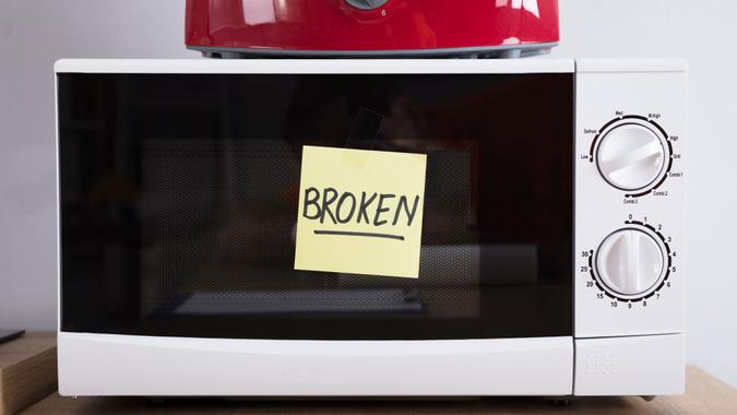 Close-up Of A Microwave Oven With Adhesive Notes Showing Broken Text.