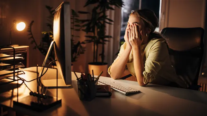 One woman, young business woman working late on computer in office at night,.