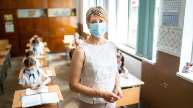Young elementary teacher wearing a protective face mask at school.
