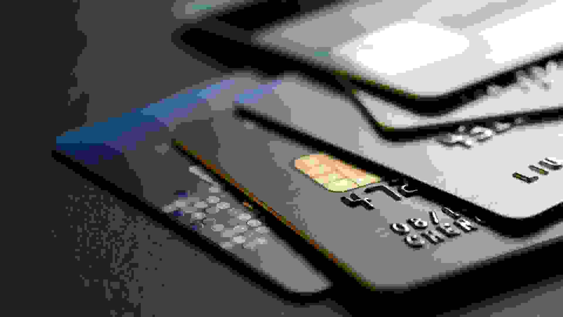 stack of multicolored credit cards on black background.